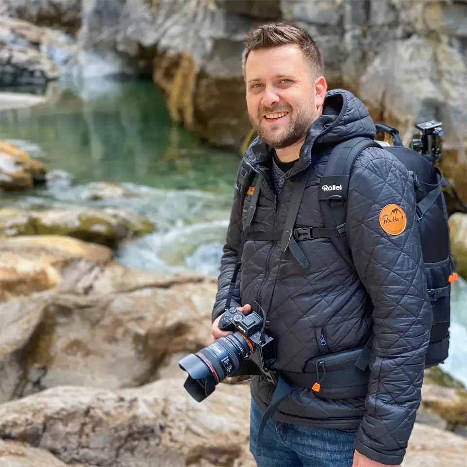 Landschaftsfotograf Robin Deimel mit Kamera und Fotorucksack in felsiger Umgebung